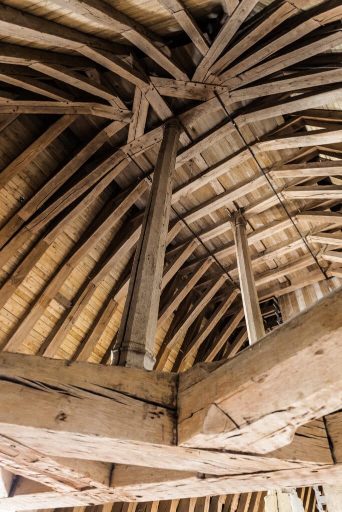 Charpente bois massif ancienne : artisanat architectural Charpente en bois ancienne et complexe d'un toit, avec un poteau central octogonal et des poutres rayonnantes. Artisanat traditionnel.